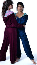 Load image into Gallery viewer, Two women modeling matching velvet lounge sets against a white studio background. The woman on the left wears a burgundy velvet jumpsuit with a floral-patterned inner top, and the woman on the right wears a dark blue velvet jumpsuit with a teal patterned inner top. Buy now online from Emma's Emporium. Baggy unisex velvet trousers with pockets. Emma's Emporium alternative hippie boho winter women's clothing. Alternative fashion, ethical, slow fashion for men and women.