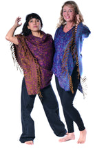 Load image into Gallery viewer, Two women modelling patterned shawls against a plain white background. The woman on the left wears a purple and orange paisley shawl with fringe, and the woman on the right wears a blue and purple patterned shawl with gold fringe. Woman in an Emma's Emporium paisley poncho with a hood and front pocket. Shop Emma's Emporium online now, ethical slow alternative hippie festival fashion and women's clothing and apparel.