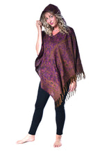 Load image into Gallery viewer, A woman modeling a dark purple and brown patterned hooded shawl or poncho with fringe, worn over black leggings against a plain white background. Woman in an Emma's Emporium paisley poncho with a hood and front pocket. Shop Emma's Emporium online now, ethical slow alternative hippie festival fashion and women's clothing and apparel.