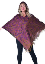Load image into Gallery viewer, A woman modelling a large purple and brown patterned shawl with fringe, shown against a plain white background. Woman in an Emma's Emporium paisley poncho with a hood and front pocket. Shop Emma's Emporium online now, ethical slow alternative hippie festival fashion and women's clothing and apparel.