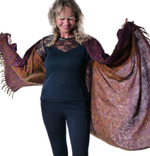 Load image into Gallery viewer, A woman modeling a large fringed shawl with a mottled pattern of purple, orange, and brown, worn open over a black top and pants against a white background. Emma's Emporium paisley fleece blanket cardigan wrap throw. Shop online and buy now ethical slow fashion, unisex, men's, women's boho festival clothing.