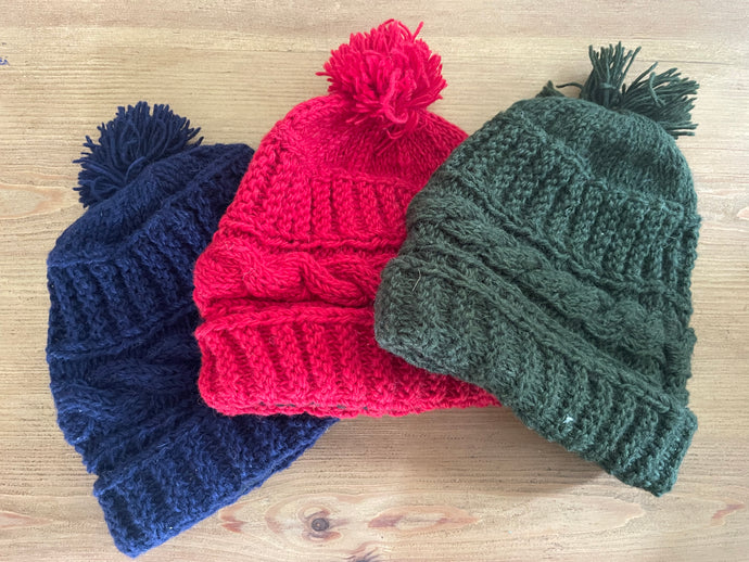 Buy now online from Emma's Emporium, Colourful Nepalese cable knit Pompom Bobble Hat! Keep your head warm this winter! Pure wool hand knitted hats in vibrant bold colours. Made for Emma's Emporium with love by our friends in Kathmandu.