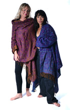 Load image into Gallery viewer, Two women standing barefoot against a white studio background, each wearing a patterned shawl or wrap draped over their shoulders. The wrap on the left is purple and brown, and the wrap on the right is blue and purple. Emma's Emporium paisley fleece blanket cardigan wrap throw. Shop online and buy now ethical slow fashion, unisex, men's, women's boho festival clothing.
