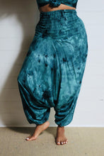 Load image into Gallery viewer, Photo of model in Emma&#39;s Emporium tie dye harem trousers, low crotch hippy trousers with wide elastic waistband on bright vibrant tie dye. Made to ethical fair trade standards for Emma&#39;s Emporium slow fashion alternative women&#39;s clothing. Festival!
