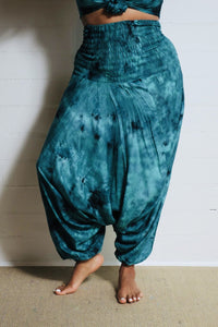 Photo of model in Emma's Emporium tie dye harem trousers, low crotch hippy trousers with wide elastic waistband on bright vibrant tie dye. Made to ethical fair trade standards for Emma's Emporium slow fashion alternative women's clothing. Festival!