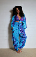 Load image into Gallery viewer, Genie Trousers! Photo of model in Emma&#39;s Emporium tie dye Genie harem trousers, low crotch hippy trousers with wide elastic waistband on bright vibrant tie dye. Made to ethical fair trade standards for Emma&#39;s Emporium slow fashion alternative women&#39;s festival clothing.
