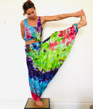 Load image into Gallery viewer, Photo of model in Emma&#39;s Emporium tie dye harem trousers, low crotch hippy trousers with wide elastic waistband on bright vibrant tie dye. Made to ethical fair trade standards for Emma&#39;s Emporium slow fashion alternative women&#39;s clothing. Festival!

